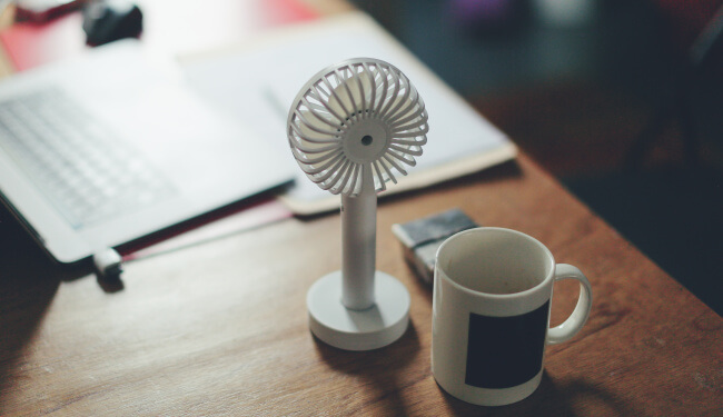 Tiny fan and mug on desk